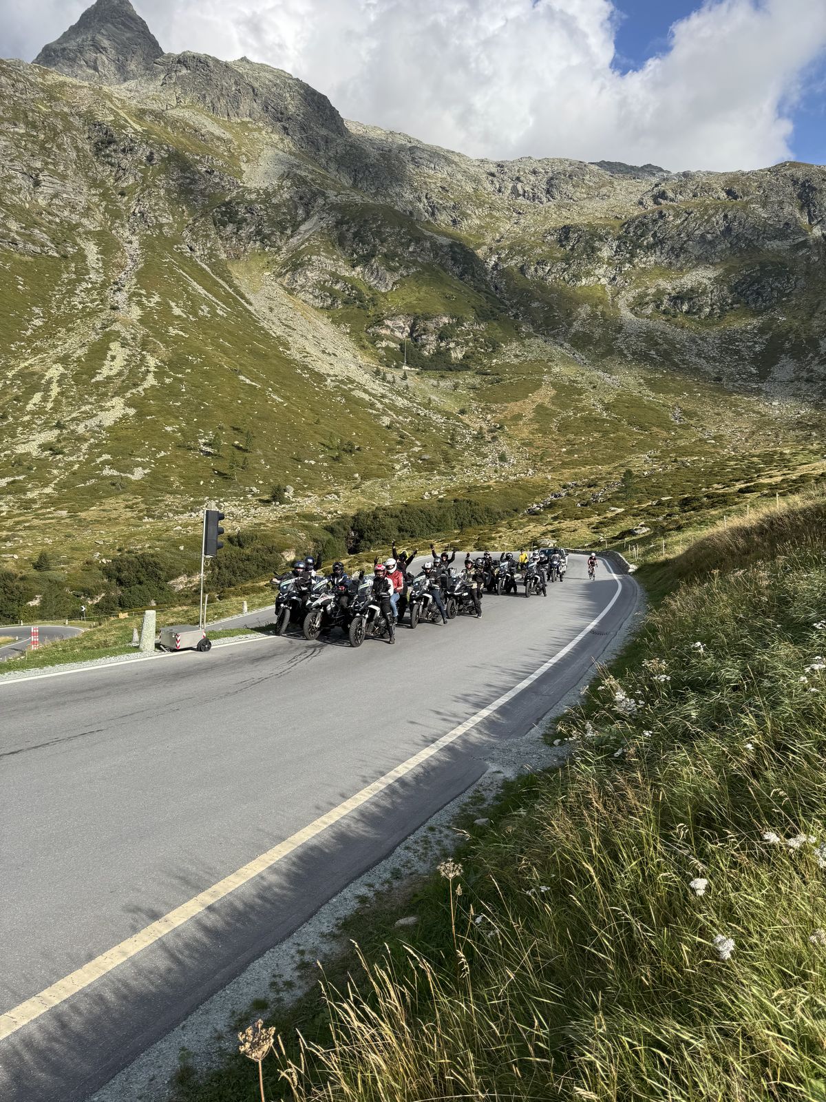 Fila de motos subindo a curva de um passo alpino