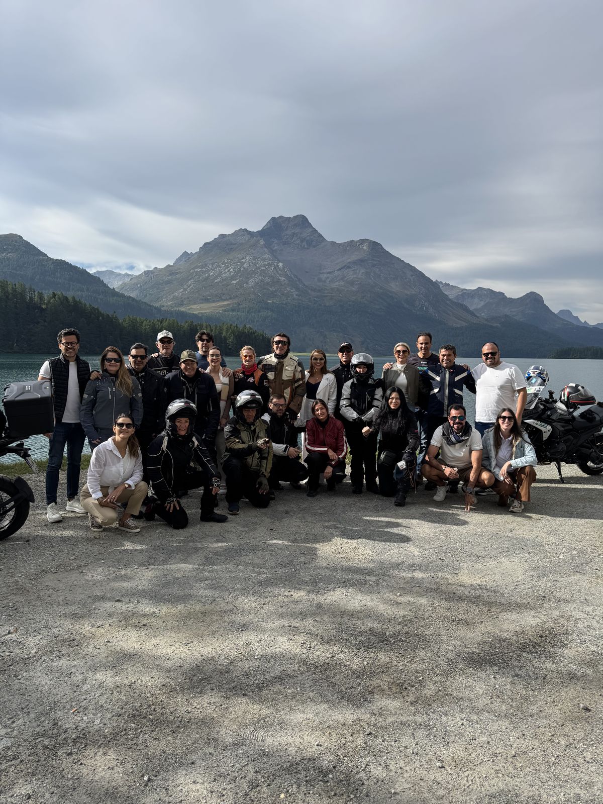Grupo com as motos à beira de um lago nos Alpes