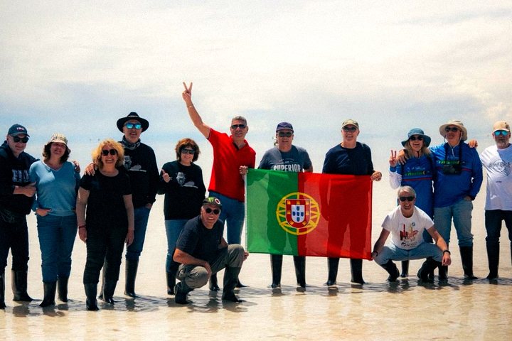 Grupo do tour com bandeira sobre o sal