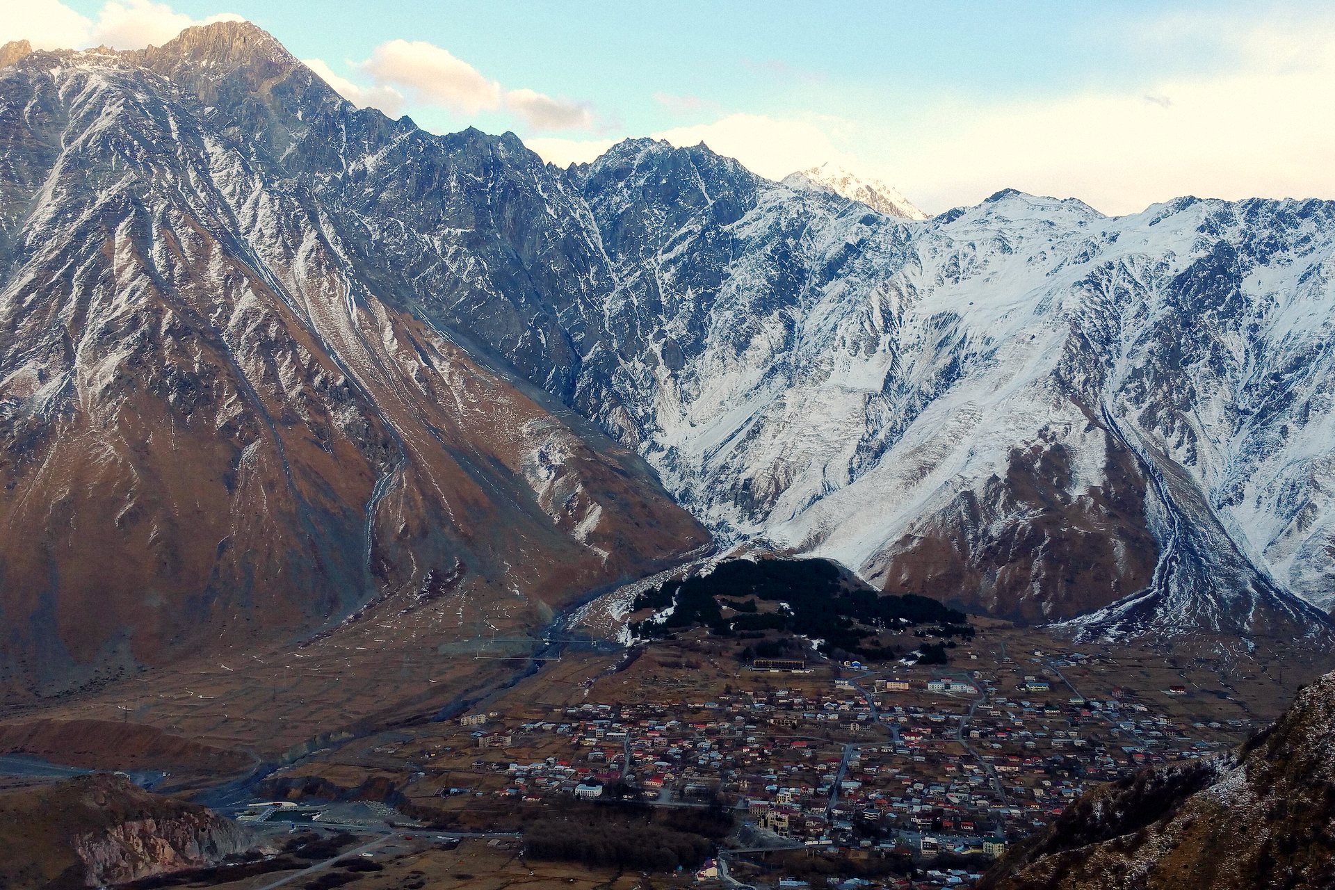 Stepantsminda no vale, ao pé das montanhas nevadas do Cáucaso