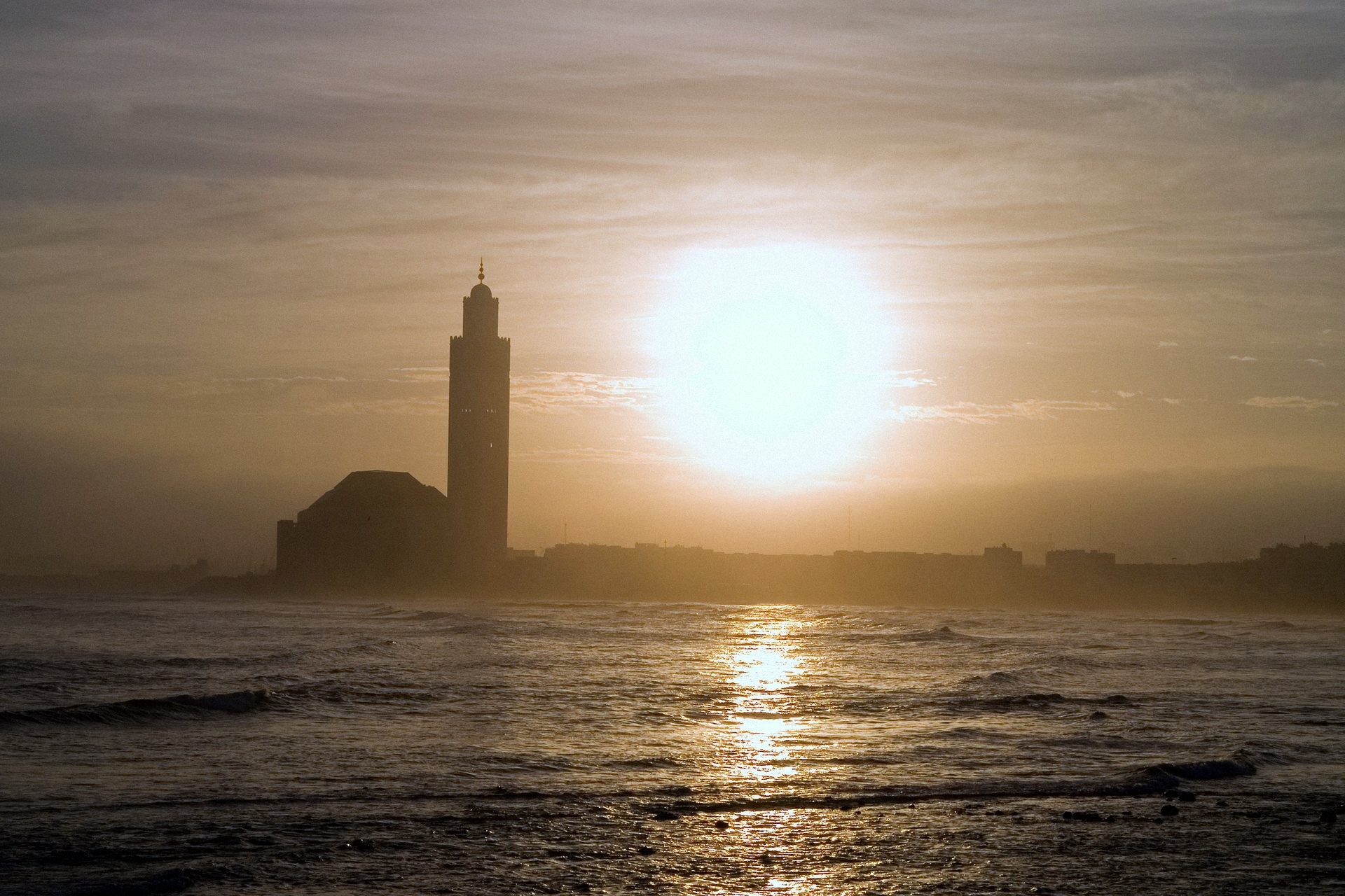 Mesquita Hassan II em silhueta contra o sol sobre o Atlântico