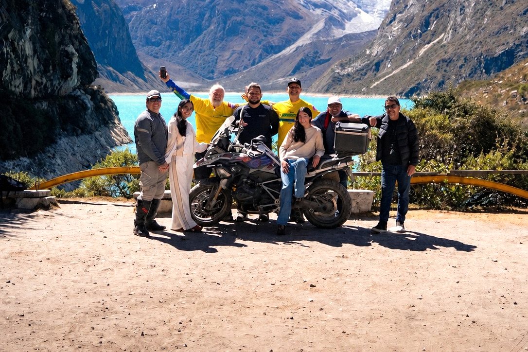 Grupo do tour em volta de uma moto diante da Laguna Parón