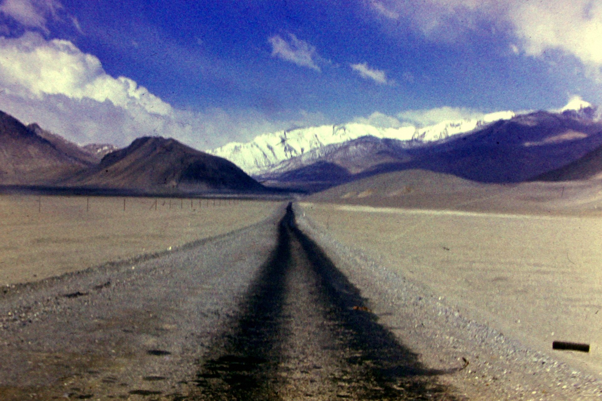 Pamir Highway atravessando o planalto perto de Murghab, com montanhas nevadas